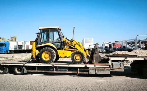 Representative construction equipment secured on a flatbed trailer